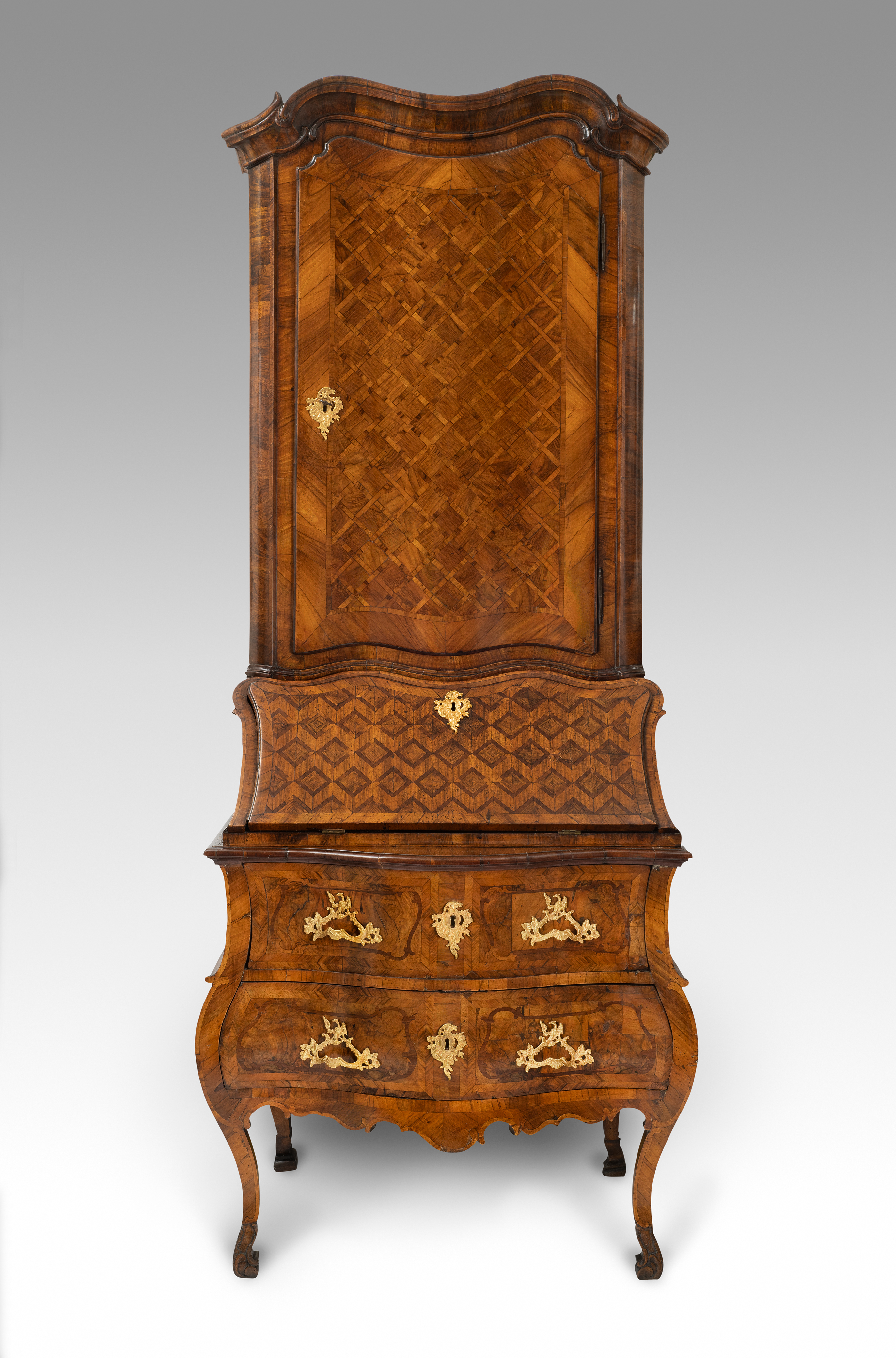 A German gilt-bronze mounted walnut and fruitwood bureau-cabinet. The parquetry-inlaid upper section enclosing a painted shelved interior over a conforming fall, and two banded drawers, with shaped apron, on angular cabriole legs. Circle of Abraham Roetgen, Rhineland, possibly Coblenz, 1750 circa.